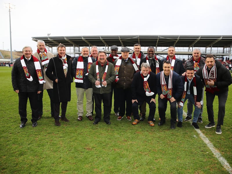 Former Northampton Town players and managers L-R Trevor Gould, Wakeley Gage, Steve Massey, Phil Chard, Peter Gleasure, Barry Tucker, Ian Benjamin, Graham Carr, Ian Sampson, Steve Phillips, Steve Brown, Ray Warburton, Scott McGleash, Ian Atkins, David Buchanan and Mark Bunn pose for a group picture after being introduced to the crowd as part of the 125th anniversary celebrations at half time during the Sky Bet League Two match between Northampton Town and Tranmere Rovers at Sixfields on March 05, 2022 in Northampton, England. (Photo by Pete Norton/Getty Images)