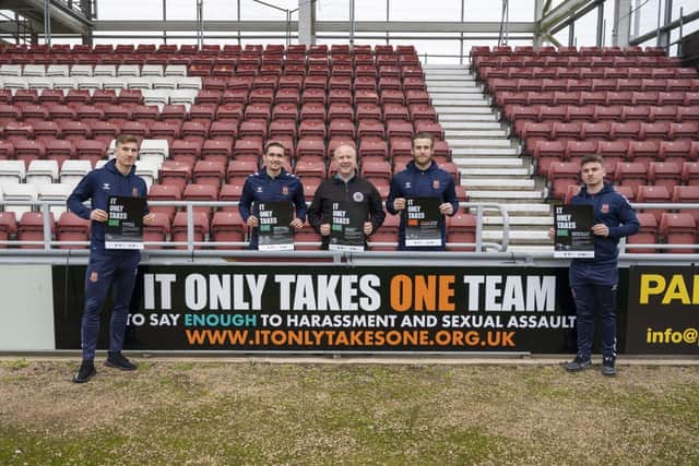 Harvey Lintott, Ben Fox, PFCC Stephen Mold, Lee Burge and Sam Hoskins stood by the 'It Only Takes One' advertising board at Sixfields. 