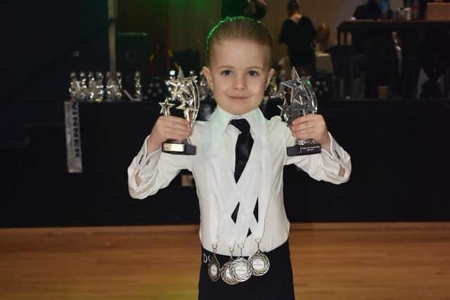 Alex Covargic proudly displays his medals and trophies after a successful dance competition.