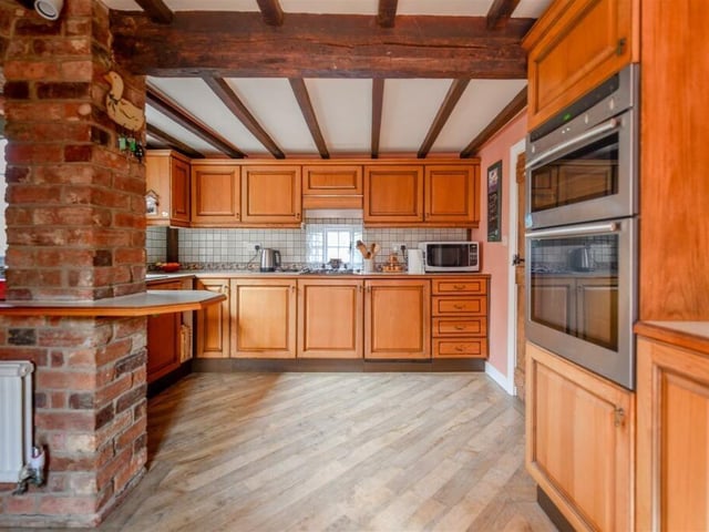 An oak wood kitchen is overflowing with potential, and includes traditional beams and exposed brick walls