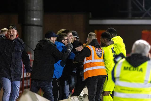 The Brackley Town players and fans celebrate their late winner at Kidderminster