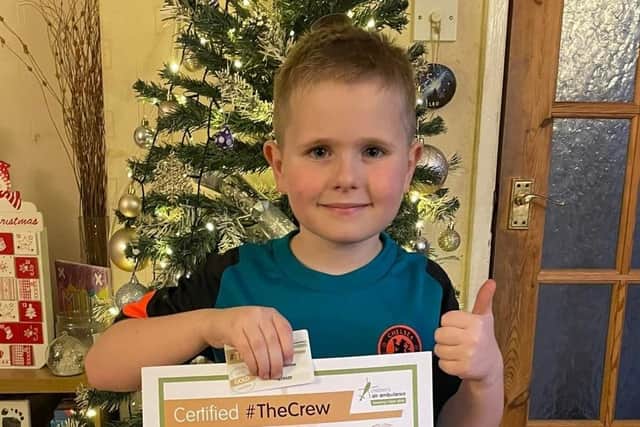 Joey Holmes, aged seven, holding his certificate after becoming a member of The Children's Air Ambulance.