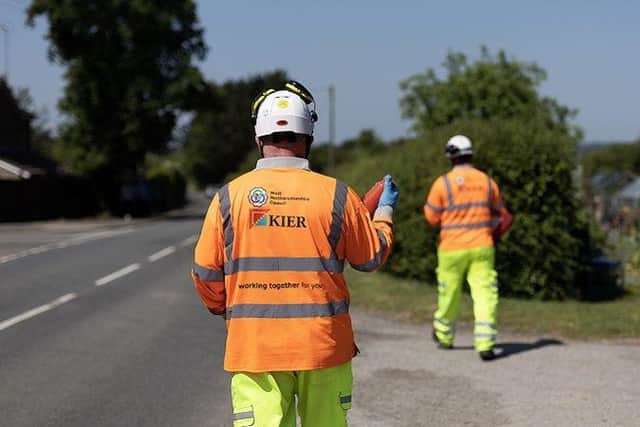 Two workers walking along a road placing cones