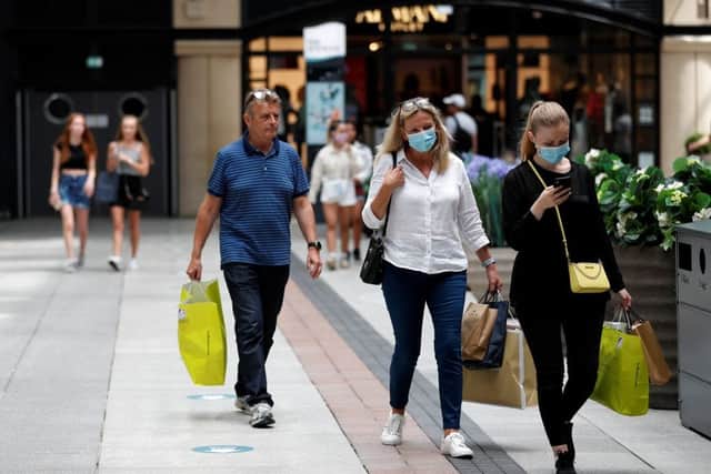 Shoppers, some wearing face masks, walk past recently reopened shops (Photo: Getty)