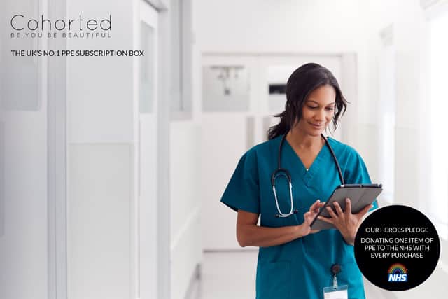 Female Doctor Wearing Scrubs In Hospital Corridor Using Digital Tablet
