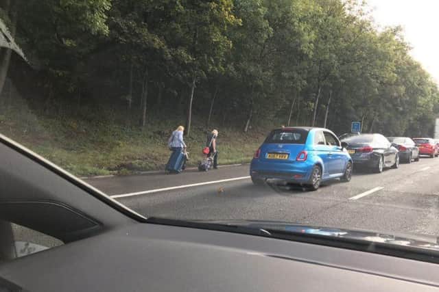 People pulling suitcases alongside stationary traffic