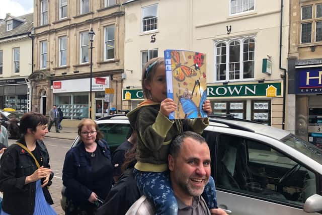 Four-year-old Roxanna pictured on her dad's shoulders holding a pretend sign.