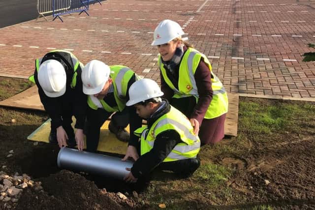 Pupils, staff and patrons from Purple Oaks bury the time capsule.