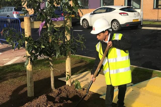 A student helps plant a new oak tree to mark the event.