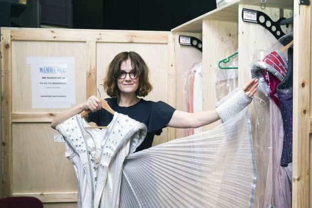Nikki holding Rosie's winged Super Trouper outfit in the quick-change spot backstage.