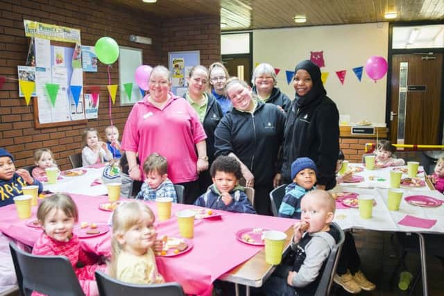 Happy staff and children celebrate Little Barn Owls first year anniversary with party food.
