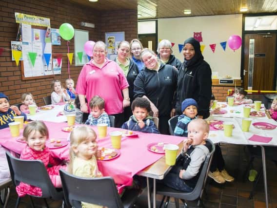 Happy staff and children celebrate Little Barn Owls first year anniversary with party food.