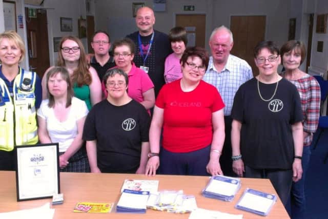 Staff and clients of Olympus Care Services helping police stuff envelopes in 2014