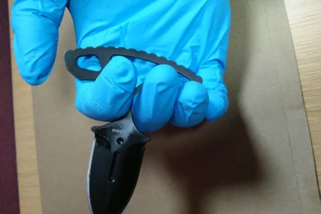 An officer holds one of the knives seized last week.