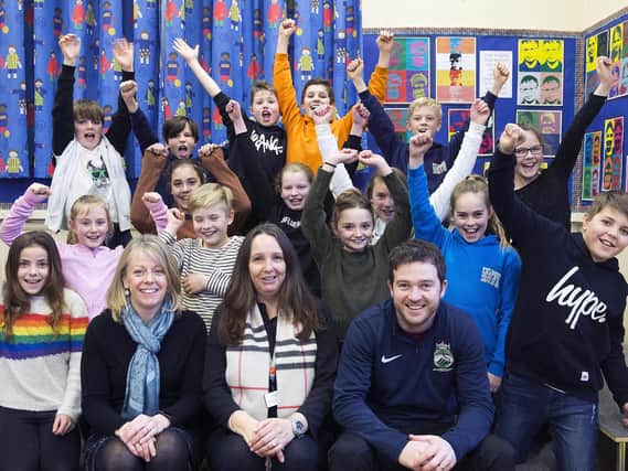 Headteacher Mrs Truslove (centre) pictured celebrating with her teaching staff and children after bagging the top spot in England for reading and maths.