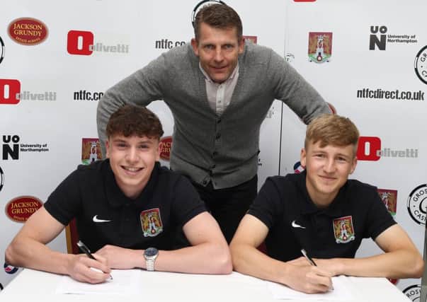 SIGNING ON - teenagers Sean Whaler (left) and Morgan Roberts sign their Cobblers contracts, under the watchful eye of boss Dean Austin (Picture: Pete Norton)