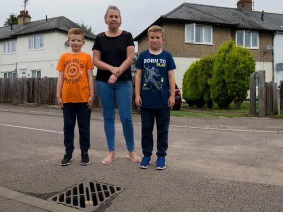 Henry, Claire, and Freddie Buswell were using their buckets and spades in the thunder and lightening - with the help of 18 neighbours in the cul-de-sac - to clear the water, which was swirling around the drain (pictured).