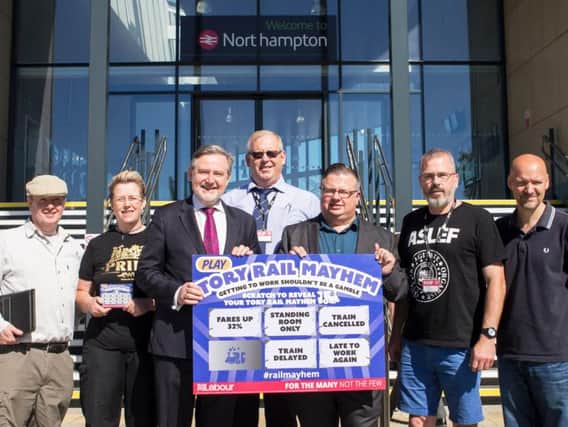 Shadow secretary for international trade Barry Gardiner and Northampton South Labour candidate Gareth Eales hold up a large version of the 'Tory Rail Mayhem' scratchcard they were seen handing out to passengers in Northampton yesterday.