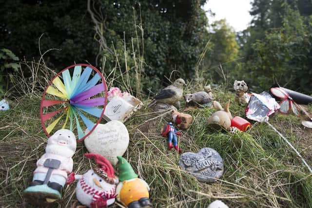 Ornaments, including action figures, personalised heart figurines and teddy bears, lay on the bank after they were collected from the ditch.