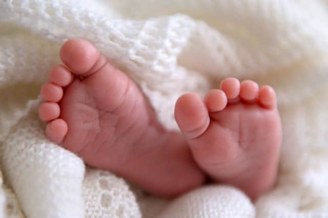 A new born baby's feet are visible peeking out of a shawl AJM_BABYSTOCK_05.jpg