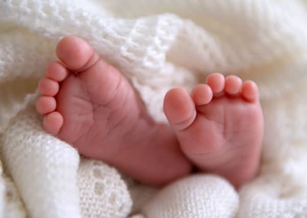 A new born baby's feet are visible peeking out of a shawl AJM_BABYSTOCK_05.jpg