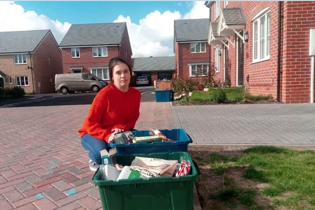 Chrissie Thomson, of Ullswater Close, kneels by some of the uncollected rubbish in recycling boxes.