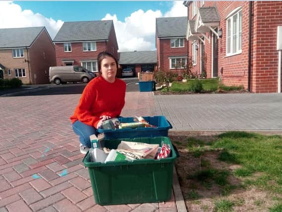 Chrissie Thomson, of Ullswater Close, kneels by some of the uncollected rubbish in recycling boxes.
