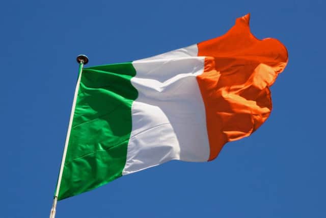 Irish flag fluttering in a brisk breeze against a bright blue sky. PPP-180731-140201006