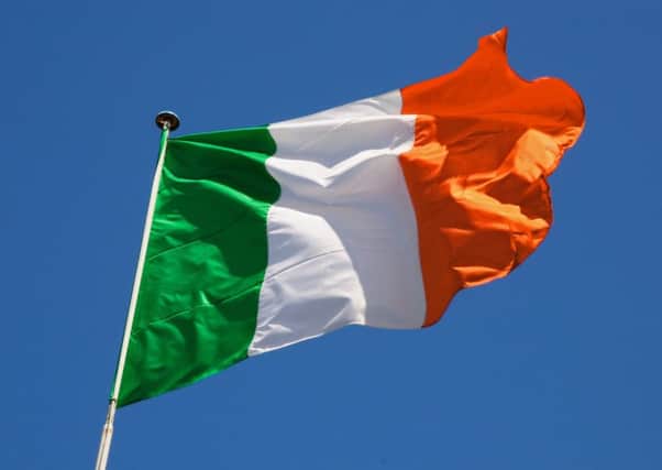 Irish flag fluttering in a brisk breeze against a bright blue sky. PPP-180731-140201006