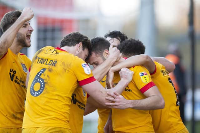 Andy Williams is mobbed by his team-mates after netting in injury-time at Stevenage