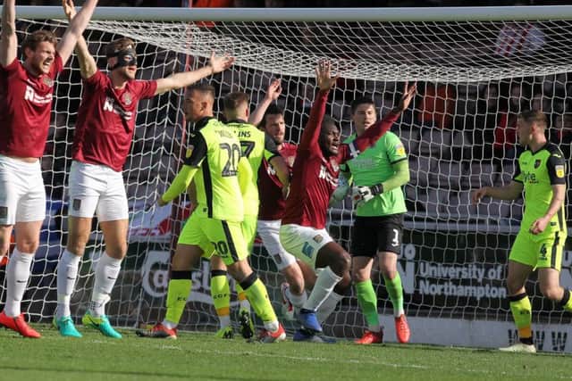 The Cobblers players appeal that the ball from Aaron Pierre's header had crossed the line