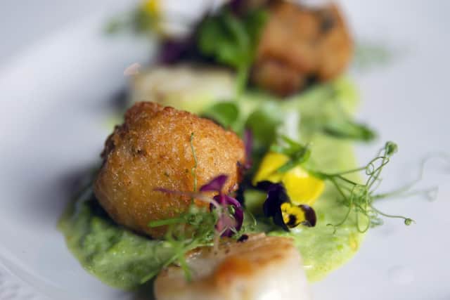Seared wild Atlantic scallops with lobster and crab bonbons, pea and truffle oil velout.