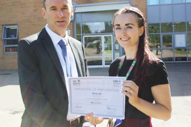 Miss Old pictured with her certificate of accreditation from the United Nations.