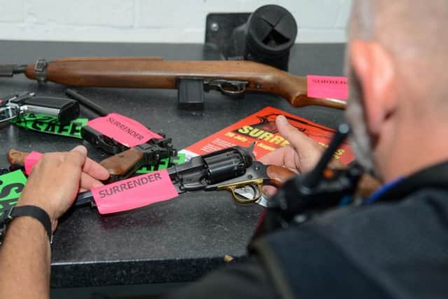 A police officer with some of the guns handed in during the amnesty so far. Photo: Northamptonshire Police