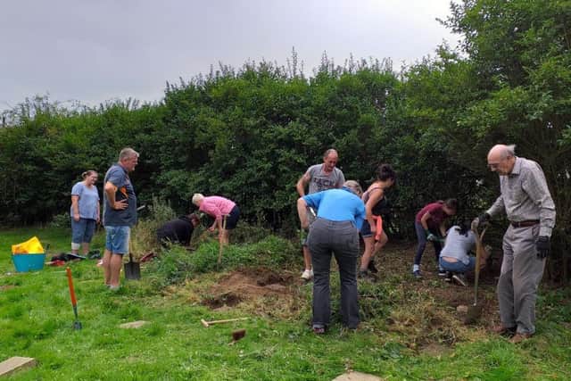 Volunteers hard at work uncovering headstones at the old St Crispin Hospital chapel. Photo: Hayley Potts