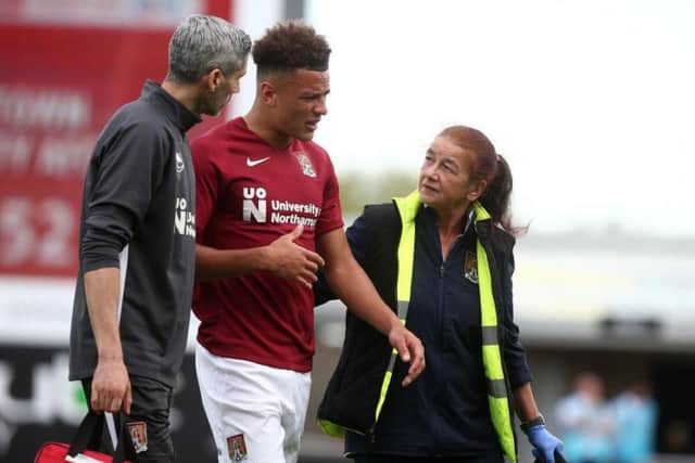 Shaun McWilliams is helped off the pitch by the Cobblers' medical staff on Saturday