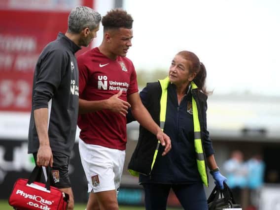 Shaun McWilliams is helped off the pitch by the Cobblers' medical staff on Saturday