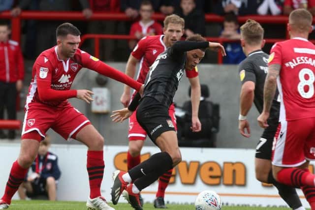 Shaun McWilliams tries to hold off two Morecambe players