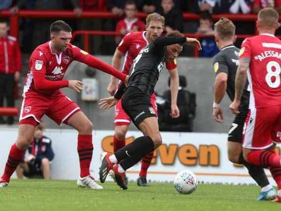 Shaun McWilliams tries to hold off two Morecambe players