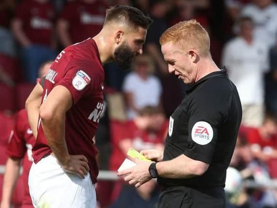 In trouble: Jordan Turnbull is booked by Alan Young during Cobblers' win over Newport last month.