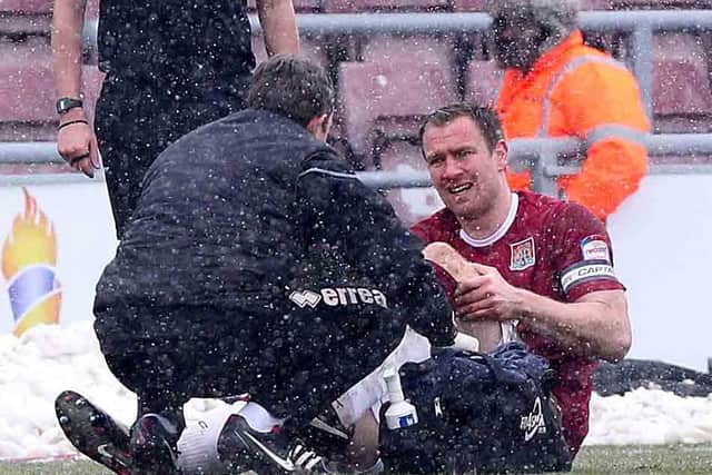 KNEE BOTHER - Cobblers skipper Kelvin Langmead receives treatment from physio Stuart Barker after injuring his knee in the 1-0 win over Oxford United on Saturday (Picture: Sharon Lucey)