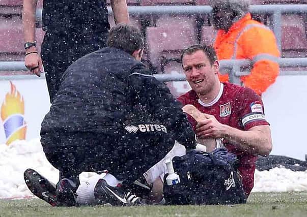 KNEE BOTHER - Cobblers skipper Kelvin Langmead receives treatment from physio Stuart Barker after injuring his knee in the 1-0 win over Oxford United on Saturday (Picture: Sharon Lucey)