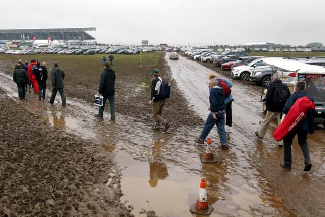 Spectators make their way through the mud as they arrive for the British Grand Prix.