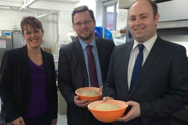 Minister for Civil Society, Rob Wilson gets a lesson bread baking with chief executive of the Good Loaf Suzy Van Rooyen, left, and Northampton South MP David Mackintosh, right.