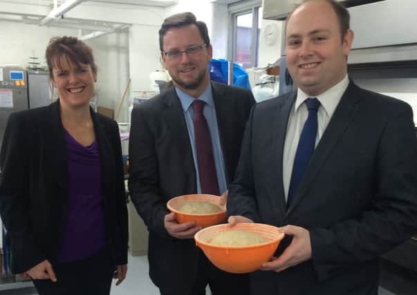 Minister for Civil Society, Rob Wilson gets a lesson bread baking with chief executive of the Good Loaf Suzy Van Rooyen, left, and Northampton South MP David Mackintosh, right.