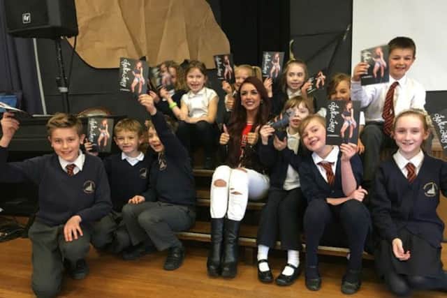 Lydia Lucy posing for photos with pupils at Kingsthorpe Village Junior School after her performance for them