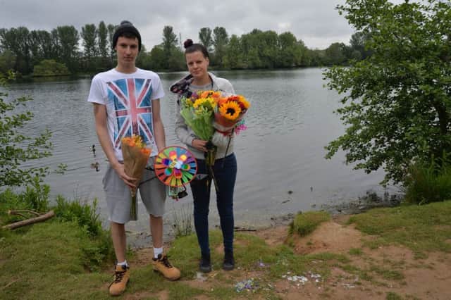 Tom Moor and Katy Seymour at Delapre Lake with some of the tributes left for their friends who died in a car crash on Sunday. The tributes would have otherwise been moved following complaints to Northampton Borough Council.