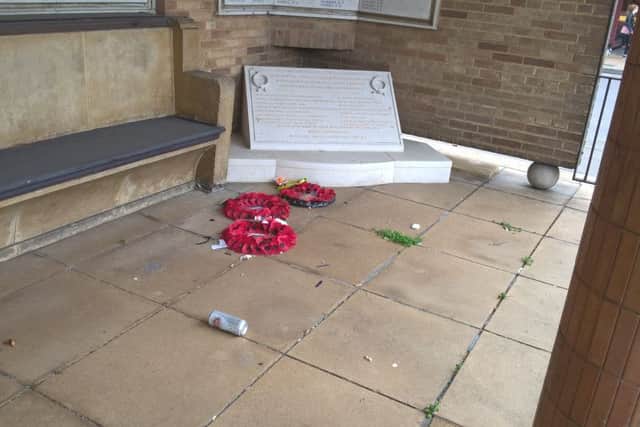 A wreath is left lying on the floor next to a beer can at the war memorial.