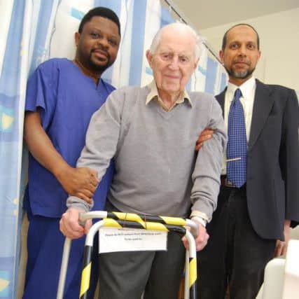 George Saxby back on his feet pictured with his surgeons - orthopaedic registrar Mr Herbert Gbejuade (left) and consultant orthopaedic surgeon Mr Shabih Siddiqui (right)