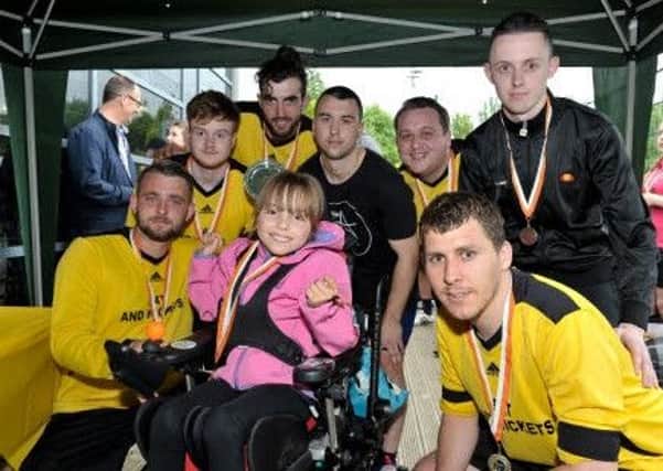 Faye Baggaley, the 100th recipient to receive a customised powered wheelchair presnts Northamptons mens team with their medals